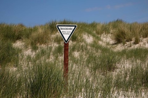 Dune landscape with sign for dune protection and the request not to enter