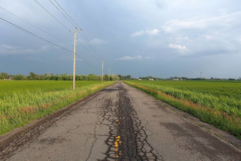Country road across fields with storm clouds
