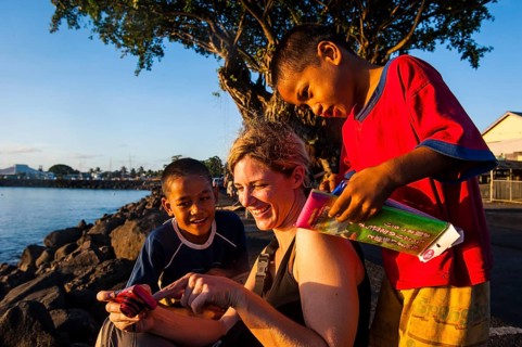 Western woman showing photos on a digi cam to local boys