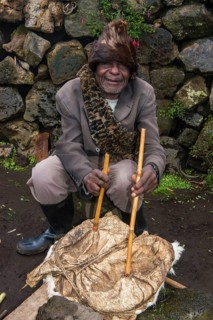 Man using animal skin to start a fire at a ceremony of former poachers