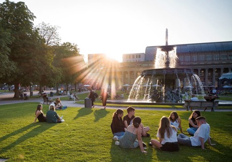 Young people enjoying summer evening on Schlossplatz in front of Koenigsbau