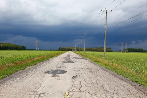 Country road across fields with storm clouds