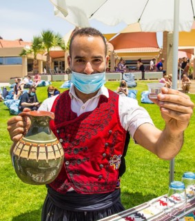 Employee with mask offers typical Cypriot liquor Zivania