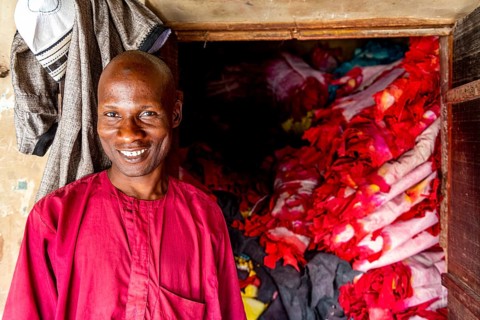 Shopkeeper before his shop full of colourful leather