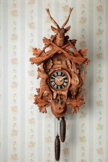Old black forest cuckoo clock in front of old fashioned wallpaper wall