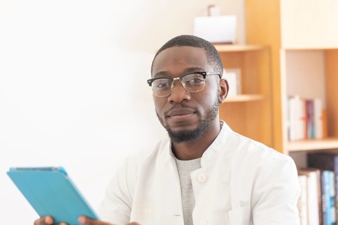 Young black doctor with smock and tablet explaining in the surgery