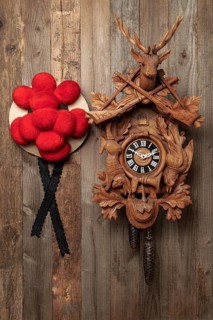 Original Black Forest cuckoo clock and Bollen hat in front of rustic wooden wall