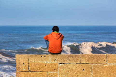 Young man sitting on the city wall