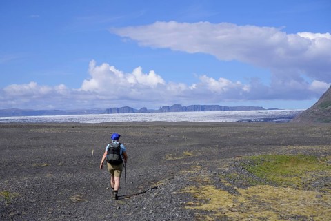 Woman hiking on a wide gravel surface in Morsardalur