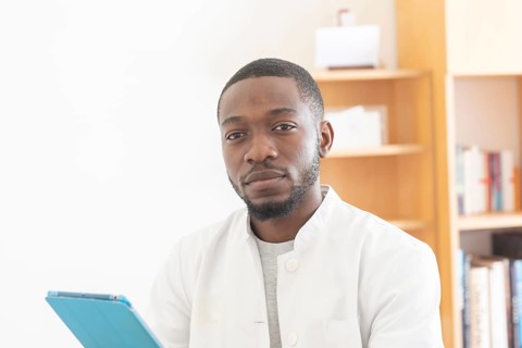 Young black doctor with smock and tablet explaining in the surgery