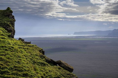 View from Hjoerleifshoefdi (Viking grave) across wide expanse of lava sand to Reynisdrangar