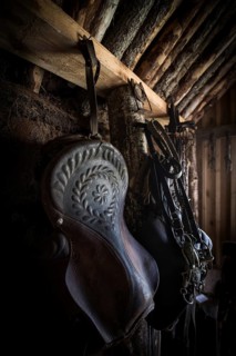 Old decorated saddle and bridle in horse stable in original peat construction