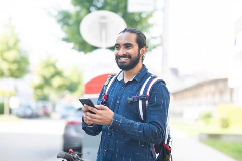 Young man with TSmart phone checks rental bike in the city