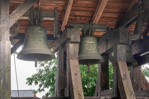 A belfry standing on the ground with four bells of different sizes in the village of Miloradz
