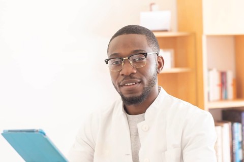 Young black doctor with smock and tablet explaining in the surgery