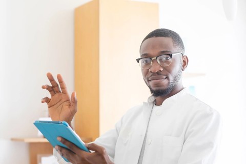 Young black doctor with smock and tablet explaining in the surgery