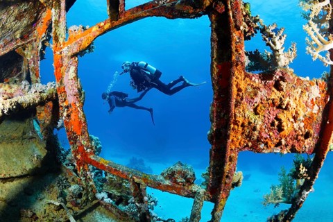 Two divers looking at shipwreck sailing ship