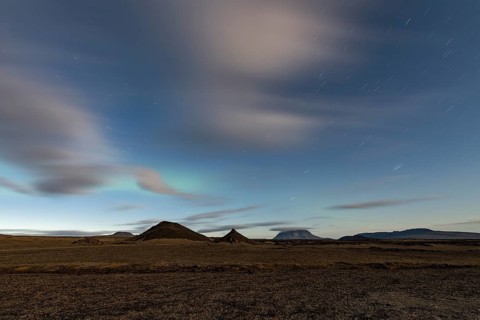 Faint northern lights (Aurora Borealis) and star trails