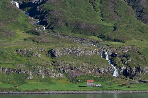 Remote farm in front of a waterfall