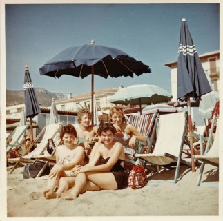 Four young German holidaymakers sitting on the beach of Finale Ligure