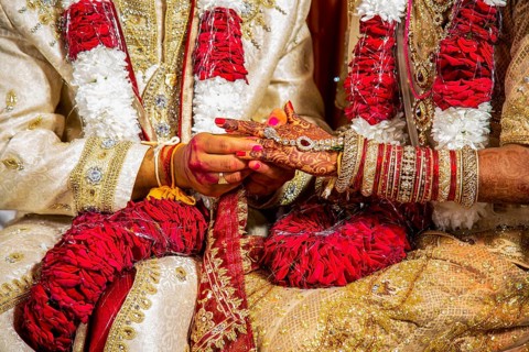 Indian groom passing wedding ring on his bride's finger on his wedding ceremony