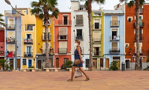 Woman walks pass Colorful beachfront houses