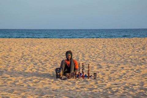 Souvenir seller sitting in the sand on the beach of Santa Maria