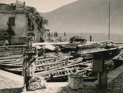 Lake Garda in 1960: young German tourist posing in front of fishing boats in the harbour