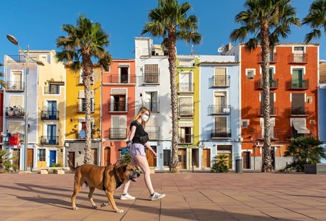 Young woman walks dog in front of Colorful beachfront houses
