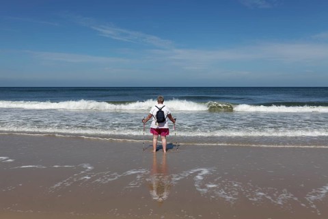 Lone beach walker looking out to sea