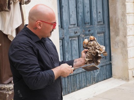 Artist creates a statue of a saint in the traditional way