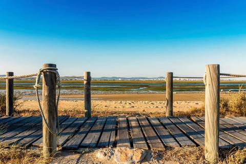 Wooden walkways with view on wetlands of Ria Formosa on Faro Beach Peninsula