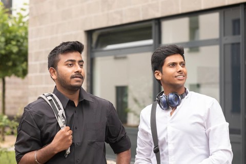 Students outside with bag in front of the university
