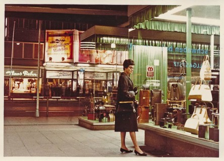 Stuttgart at night in 1963: A young woman with a coat and handbag looks at the display of handbags and suitcases in a leather goods shop