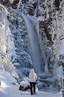 Hiker in front of an icy waterfall