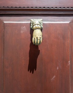 Door knocker in the shape of a hand on a brown door