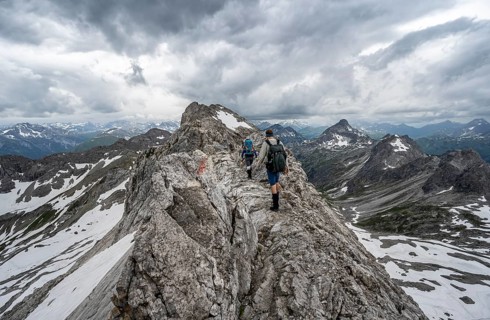 Hiker and hiker on a ridge trail with remnants of snow