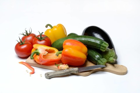 Ingredients for ratatouille on wooden board with knife