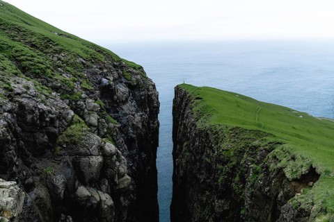 Small person standing on cliff with deep crevice