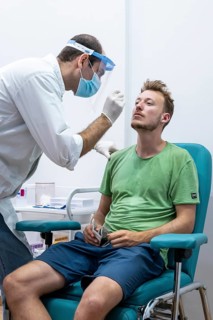 Doctor in protective clothing does an antigen test on a young man
