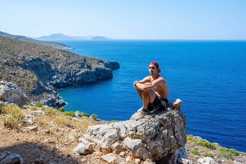 Young man sitting on a rock on the coast