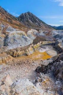 Crater with yellow discoloured sulphur stones and colourful mineral deposits
