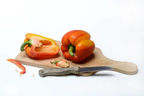 Yellow-red coloured peppers (Capsicum) on wooden board