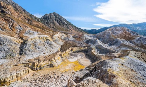Crater with yellow discoloured sulphur stones and colourful mineral deposits