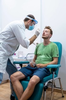 Doctor in protective clothing does an antigen test on a young man