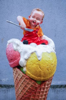 Advertising figure in front of an ice cream parlor: small child sitting in an ice cream cone
