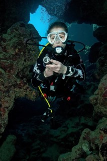 Young woman with scuba diving equipment dives into cave
