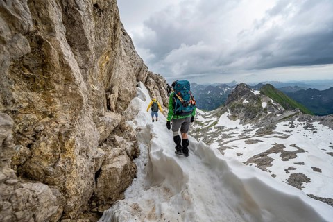 Hiker and hiker on snow remains in rocky terrain