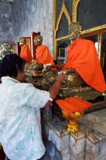 Believers paste statues of monks with gold leaf