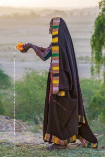 Ahir woman in traditional colorful cloth pouring water